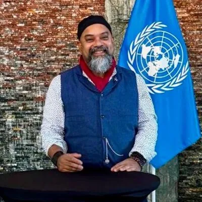 Atif Choudhury speaking at a podium beside a United Nations flag