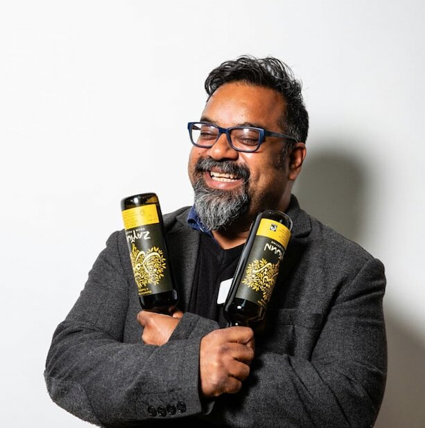 Atif Choudhury laughing while hugging two bottles of Zaytoun olive oil